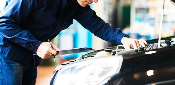 Mechanic-With-Clipboard-Examining-Car