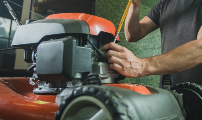 Man checking the oil in his lawn mower.