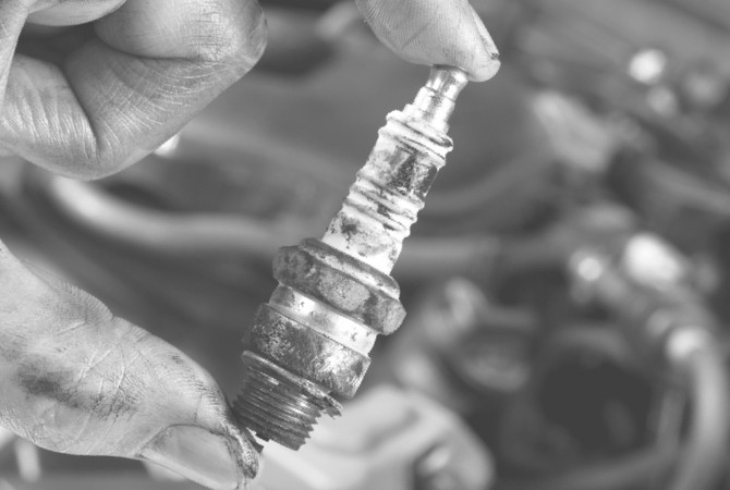 An extremely dirty spark plug that is covered in dark oil