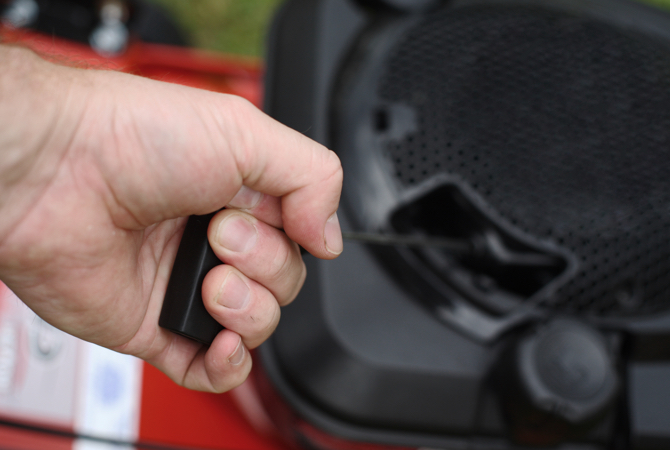 Hand pulling the starting cord on a lawn mower engine.