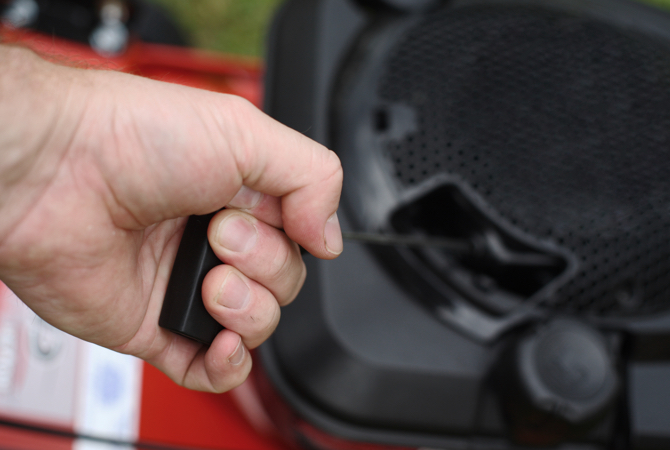 Starting-Lawnmower Hand pulling the starting cord on a lawn mower engine.