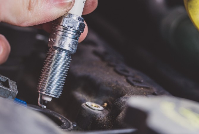 mechanic-installing-spark-plug Hand holding a spark plug
